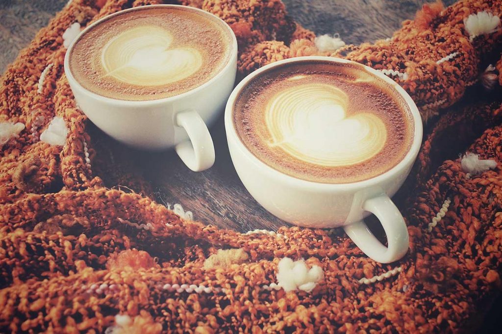 two coffee cups with hearts made of cream on a table.