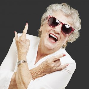 Older woman wearing a big smile and sunglasses.