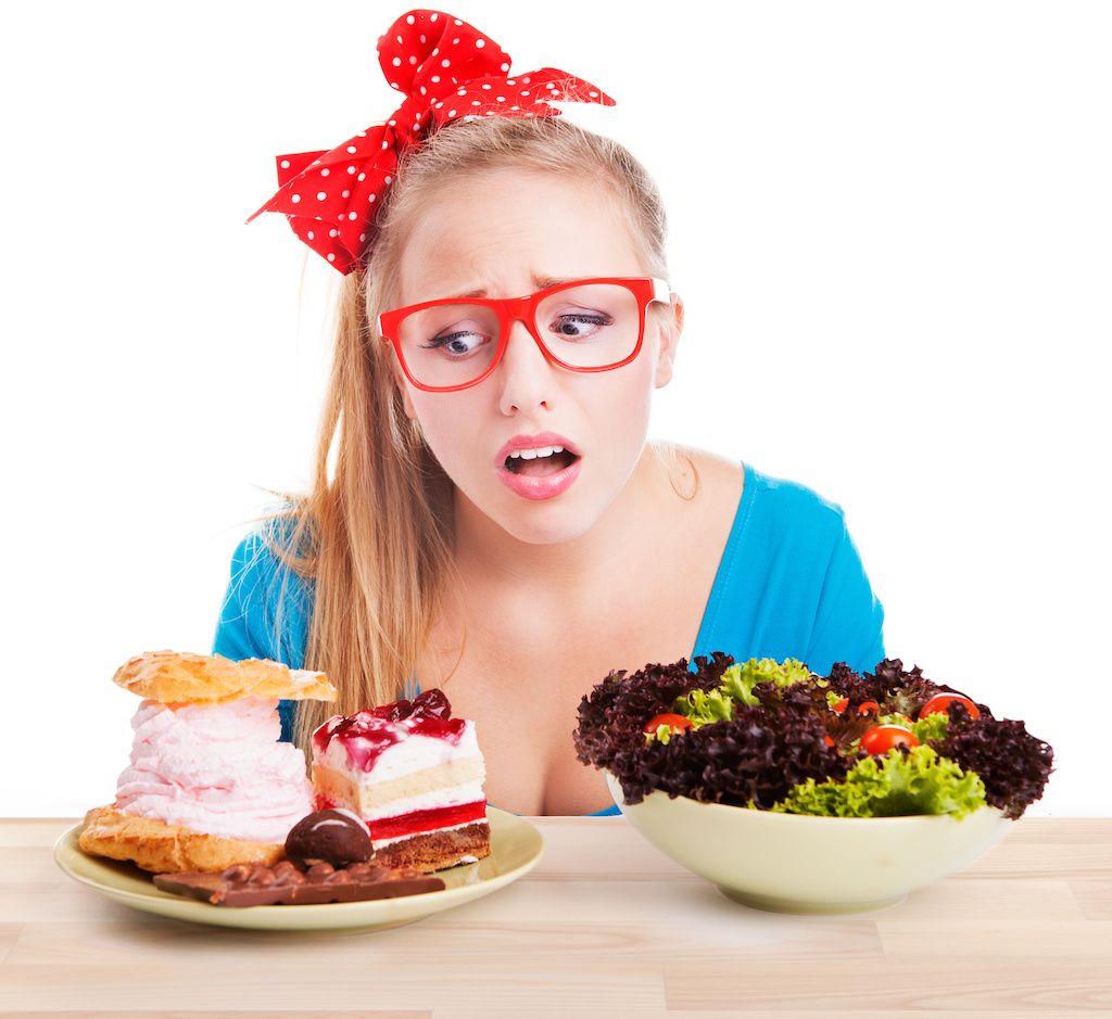 woman with red glasses looking longingly at sweets with a salad on the other side