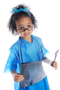 Cute little girl dressed as a medical care provider reading an x-ray
