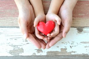 Adult and child hand holding a pretty heart - Teen World Confidential