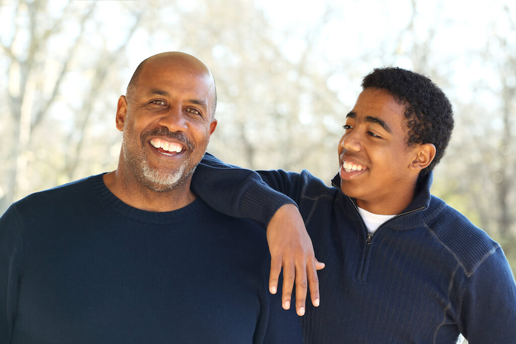 Teen son and dad smiling