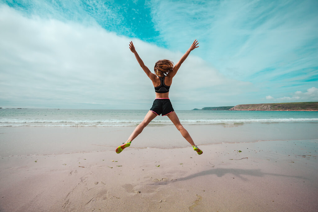 Woman jumping on beach - Teen World Confidential