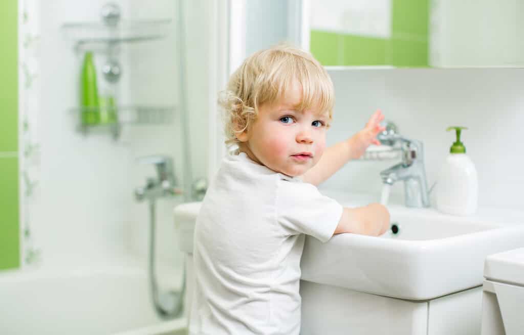 Little boy is washing his hands to prevent illness.
